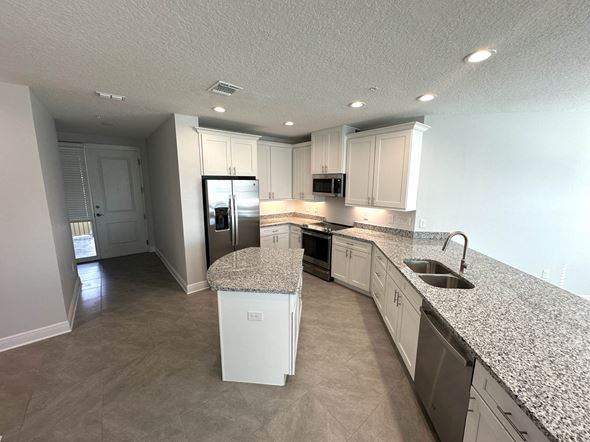 Bradenton house for rent - a kitchen with white cabinets and granite counter tops