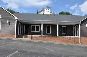Winchester apartment for rent - A building with a grey roof and a brick wall with a black iron fence in front.