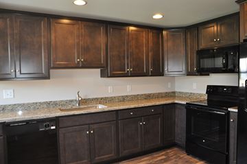 Winchester apartment for rent - A kitchen with dark wood cabinets and black appliances.