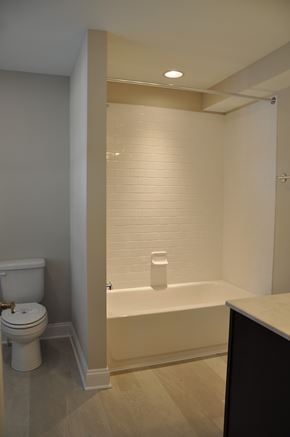 Winchester apartment for rent - A white toilet sits next to a white bathtub in a bathroom.