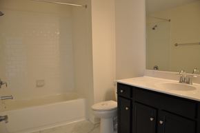 Winchester apartment for rent - A white tiled bathroom with a black vanity and a white toilet.