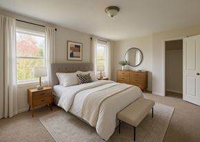Winchester townhouse for rent - A bedroom with a large bed, a nightstand with a lamp, and a window with curtains.