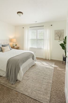 Winchester townhouse for rent - A bedroom with a bed, a lamp, a plant, and a painting on the wall.