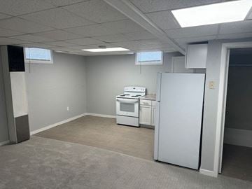 Wahpeton apartment for rent - A kitchen area with a refrigerator, oven, and microwave in a room with carpeted floor.