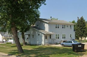 Wahpeton apartment for rent - A white house with a blue car parked in front.