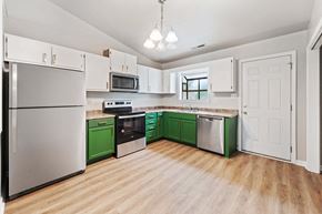 Jacksonville house for rent - a kitchen with green and white cabinets and appliances