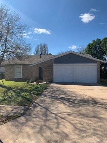 Austin house for rent - a brick house with a white garage and a driveway