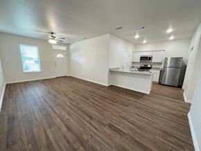 Killeen apartment for rent - an empty living room with a kitchen and a ceiling fan