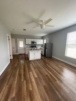 Austin apartment for rent - an empty living room and kitchen with hardwood floors and a ceiling fan