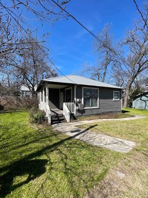 Austin apartment for rent - a small gray house with a porch and a grassy yard
