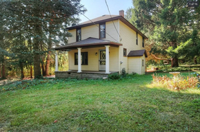 Comstock Park house for rent - a yellow house with a lawn and trees
