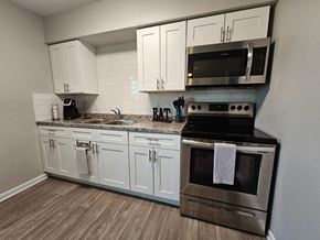 Killeen apartment for rent - A kitchen with white cabinets and a black microwave above the stove.