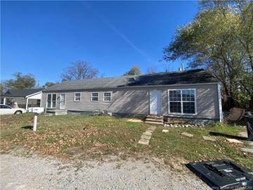 Charlestown house for rent - A house with a gray roof and white trim is surrounded by a gravel driveway and a grassy yard.