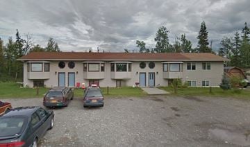 Palmer apartment for rent - A building with a gravel driveway and four cars parked in front.
