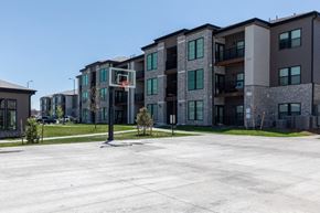 Denver apartment for rent - A basketball court is in the middle of a parking lot in front of apartment buildings.