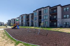 Denver apartment for rent - A playground with a swing set in front of apartment buildings.