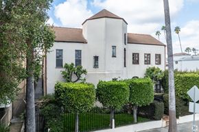 Los Angeles apartment for rent - A white building with a brown roof and a black fence in front of it.