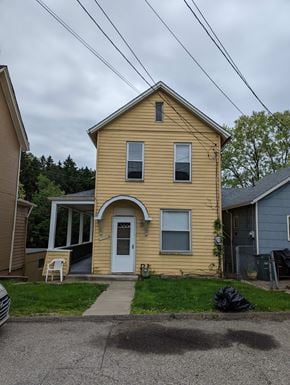 White Oak house for rent - A yellow house with a white door and a small porch.