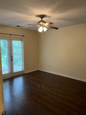 Newnan house for rent - an empty living room with a ceiling fan and wood floors