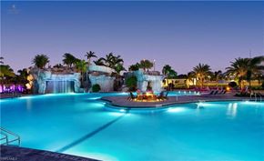 Estero house for rent - a resort pool with a waterfall and a fire pit at night