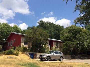 Austin apartment for rent - A silver car is parked in front of a red house.