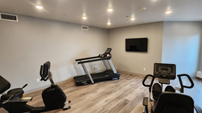 Fargo apartment for rent - a gym with cardio equipment and a tv on the wall