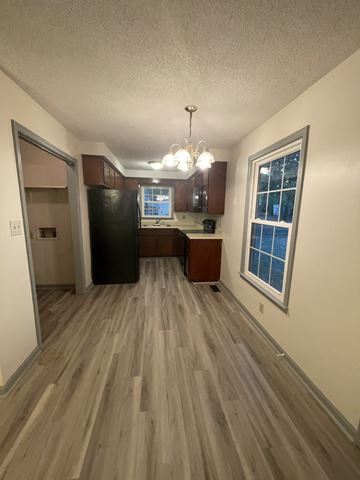 Clarksville house for rent - A kitchen with wood flooring and a black refrigerator.
