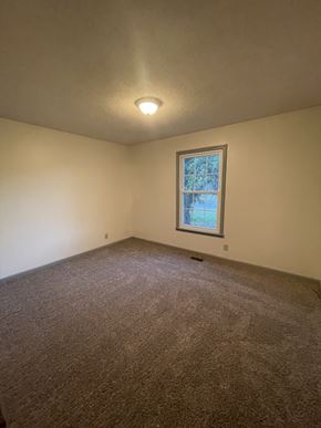 Clarksville house for rent - A room with a carpeted floor and a window with a view of trees outside.
