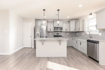 Clarksville house for rent - a renovated kitchen with white cabinets and a large island