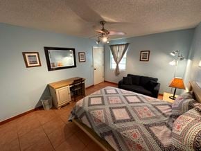 Bradenton house for rent - a bedroom with a bed and a chair and a ceiling fan