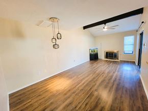 Killeen house for rent - the living room and dining room of an empty house with wood floors and a fireplace