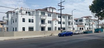 Valley Village apartment for rent - a blue car parked on a street in front of white buildings