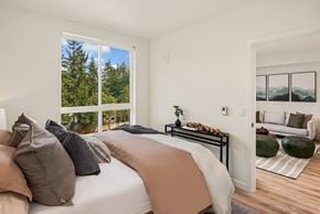 Kirkland apartment for rent - A bedroom with a large bed and a view of trees outside the window.
