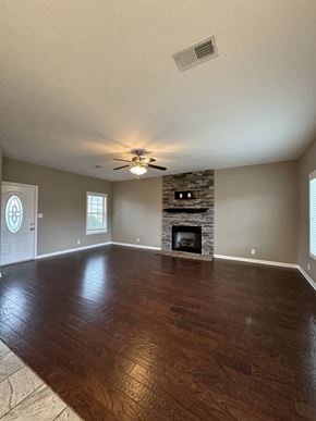 Clarksville house for rent - an empty living room with a fireplace and a ceiling fan