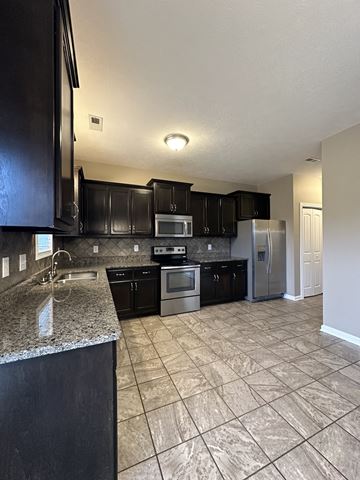 Clarksville house for rent - a kitchen with black cabinets and stainless steel appliances