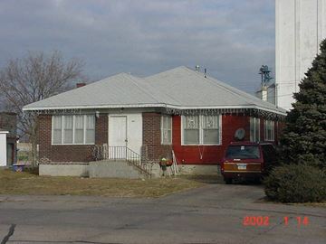 Grand Island apartment for rent - A house with a red brick exterior and a grey roof with a car parked in front.
