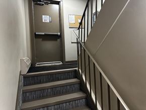 Grande Prairie apartment for rent - A staircase with a metal railing and a black carpeted stair tread.