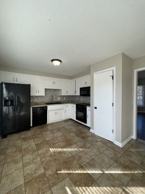 Clarksville house for rent - A kitchen with black appliances and white cabinets.