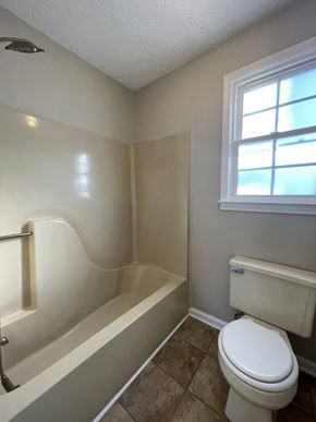 Clarksville house for rent - A white toilet sits next to a bathtub in a bathroom.