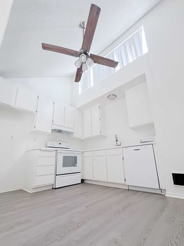 Cypress apartment for rent - A white kitchen with a ceiling fan and a microwave oven.