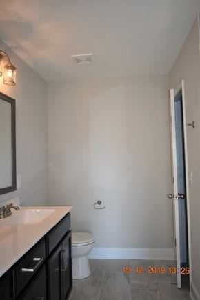 Clarksville house for rent - A bathroom with a toilet, sink, and mirror.
