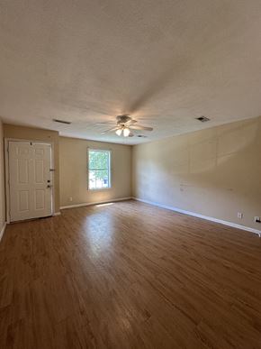 Clarksville house for rent - an empty living room with wood floors and a ceiling fan