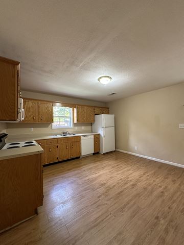 Clarksville house for rent - an empty kitchen with wooden cabinets and a stove and refrigerator