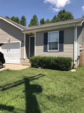 Clarksville house for rent - A house with a white garage door and a grey house with a brown roof.