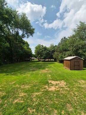 Oak Grove house for rent - A grassy field with a shed and trees in the background.