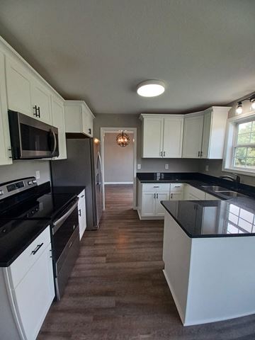 Clarksville house for rent - A kitchen with black countertops and white cabinets.
