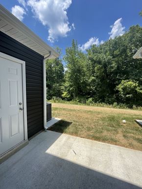 Clarksville house for rent - a garage door on the side of a house with a lawn and trees