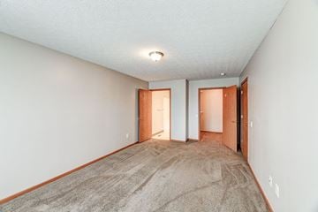 Tiffin apartment for rent - a spacious living room with carpet and a door to a hallway