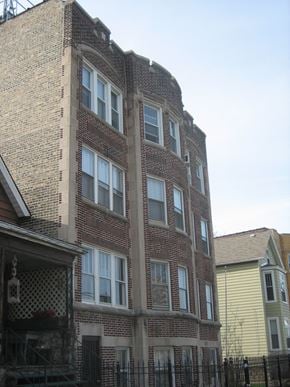 Chicago apartment for rent - the side of a brick building with windows and a fence