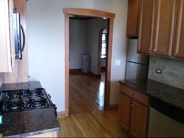 Chicago apartment for rent - the kitchen and living room of a house with wood flooring and a stove